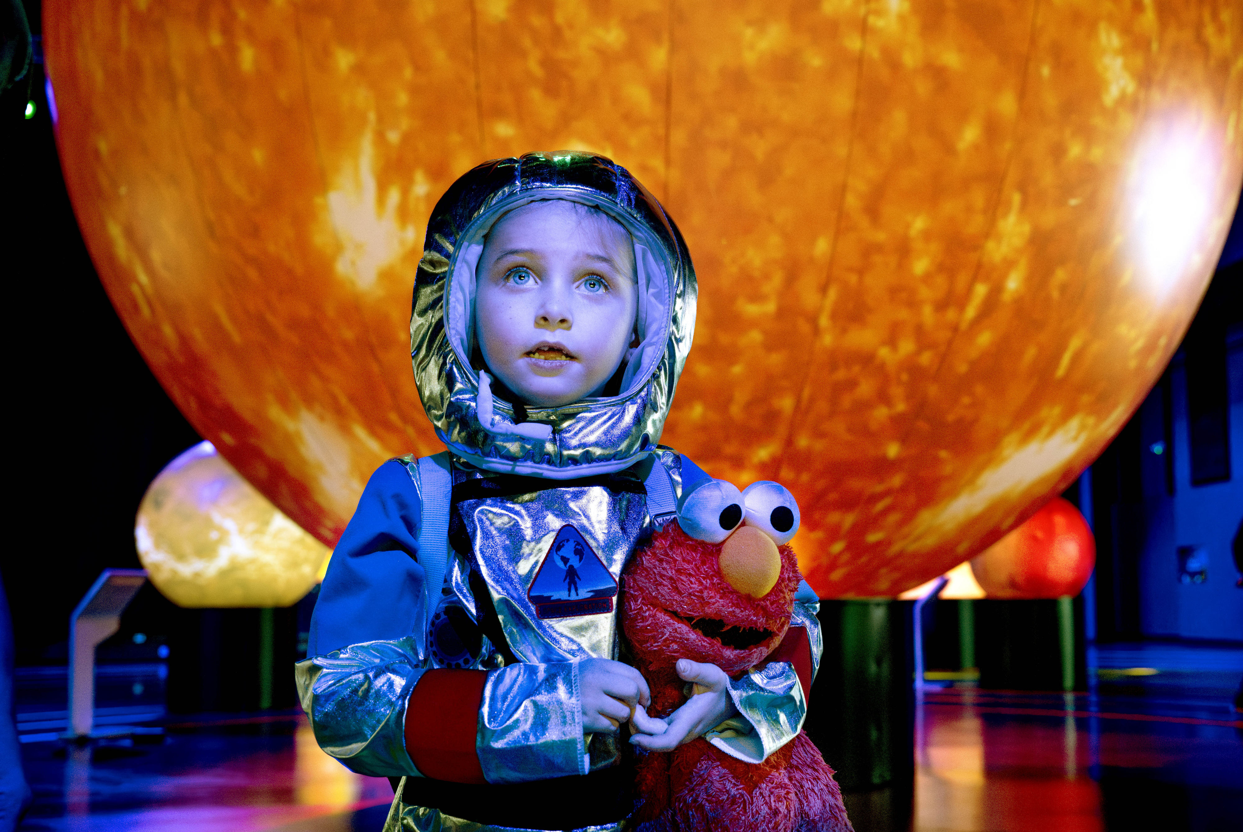 Vestido como un astronauta y sosteniendo su muñeco de peluche Elmo,…