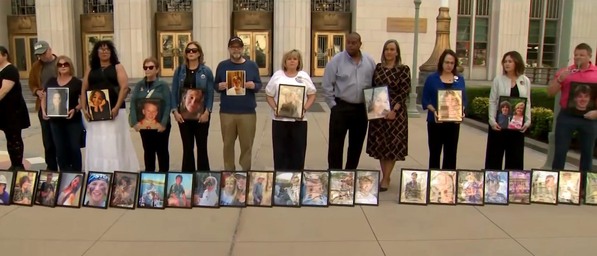 Un grupo de padres sostiene fotografías enmarcadas de sus hijos fallecidos en una vigilia.